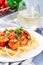 Italian dish shrimp linguine Puttanesca, pasta with shrimps in spicy tomato basil sauce garnished with parsley, vertical