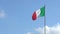 Italian flag waving in wind on flagpole with a seagull flight in background