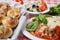 Italian food combination of lasagna, small side salad and garlic knots with whole raw vegetables  on the background