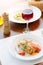 Italian food - delicious lasagne in white plate on table with red wine.