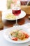 Italian food - delicious lasagne in white plate on table with red wine.