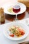 Italian food - delicious lasagne in white plate on table with red wine.