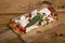 Italian food.Homemade rectangular pizza slice with basil, fresh buffalo mozzarella and tomatoes on wooden board