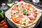 Italian food. Pizza with ingredients, spices, oil and vegetables on dark background. Flat lay, top view.