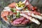 Italian food, prosciutto, grissini, smoked sausage, ham, olives, capers, sun-dried tomatoes on wooden background