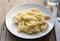 Italian four cheese pasta on the white plate on the rustic table with a fork on a side.