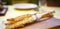 Italian grissini close-up on a wooden plank against a yellow tablecloth and cutlery in an Italian restaurant