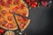 Italian homamade pizza with one piece and ingredients. Italian pizza on a dark gray black background