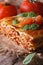 Italian lasagna with basil close-up on paper, vertical rustic