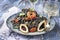 Italian linguine con tinta de calamari and prawns with olives on a modern design plate