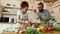 Italian man adding pepper, spice to the soup while woman stirring it with a spoon. Couple preparing a meal together in