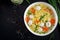 Italian meatball soup and Stelline gluten free pasta in bowl on black table.