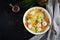 Italian meatball soup and Stelline pasta in bowl on black table.