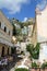 Italian narrow street between houses, stairs leading up and restaurants with tables outside