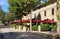 Italian outdoor cafe with umbrellas and flower pots in small tow