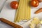 Italian pasta Cooking Still Life. Dry spaghetti or macaroni, oliv oil, tomatoes, green and cheese on wooden kitchen table. Selecti
