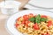 Italian pasta farfalle with pesto sauce, tomato, basil and pepper. Bowl with grated parmesan cheese and kitchen towel.