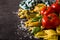 Italian pasta and ingredients. Ravioli, penne pasta, spaghetti, tortellini, tomatoes and basil on black background.