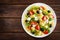 Italian pasta salad with fresh tomato, cheese, lettuce and olives on wooden background. Mediterranean cuisine. Cooking lunch. Hea