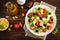 Italian pasta salad with fresh tomato, cheese, lettuce and olives on wooden background. Mediterranean cuisine. Cooking lunch. Hea