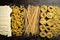 Italian pasta shapes, spaghetti, fusilli, tagliatelle, lasagna, penne, raw Italian pasta on a wooden background