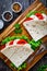 Italian piada wraps - piadina stuffed with fresh lettuce mozzarella and sliced tomatoes on wooden table