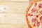 Italian pizza capriciosa lies on baking paper, on a wooden background, copyspace