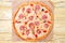 Italian pizza capriciosa lies on baking paper, on a wooden background, top view