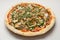 Italian pizza with chicken and mushrooms, poured with pesto, close-up