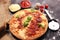 Italian pizza with salami, peperoni - with melted cheese, red tomatoes and green basil on a table decorated by cheese, tomato and