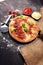 Italian pizza with salami, peperoni - with melted cheese, red tomatoes and green basil on a table decorated by cheese, tomato and