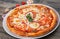 Italian pizza with tomato topped with melted golden cheese, herbs and basil