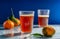 Italian refreshing beverage Chinotto in two glasses over glass grey surface with citrus fruits and dark blue background