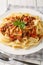 Italian Reginette pasta with bolognese sauce closeup on the plate on the wooden table. Vertical