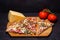Italian rustic pizza, three pieces on a wooden tray, dark wooden table, with tomatoes and cheese