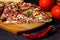 Italian rustic pizza, three pieces on a wooden tray, dark wooden table, with tomatoes, cheese and chili