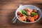 Italian salad of sliced tomatoes, basil leaves, olives, large pieces of croutons. In a deep plate, on a dark background