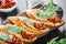 Italian sandwiches - bruschetta with meat pate, arugula, sun dried tomato and seeds on ciabatta bread on dark wooden table.