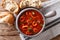 Italian thick tomato soup with squids close-up, served with bread. Horizontal top view
