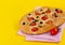 italian tortilla focaccia with tomatoes, herbs and olives, on a bright yellow background