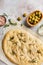 Italian traditional focaccia bread baking with aromatic seasonings and rosemary on a light gray background.