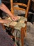 Italian traditional handicraft: woman making a straw seat for wooden chair