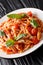 Italian Trofie pasta with tomatoes, parmesan and basil close-up in a plate. vertical