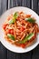 Italian Trofie pasta with tomatoes, parmesan and basil close-up in a plate. Vertical top view