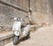 Italian Vespa brand scooter leaning against an old wall in the city center