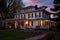 italianate mansion with deep eaves at dusk, lights shining from windows