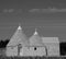 Italy. Traditional dry stone conical roofed trulli house in a field of flowers near Alberobello. Photographed in monochrome.