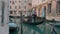 Italy, Venice, February 2019. Side view shot of a lonely gondolier rowing an empty boat in a narrow street canal in