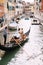 Italy wedding in Venice. A gondolier rolls a bride and groom in a classic wooden gondola along a narrow Venetian canal