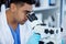 Itll be clearer once I magnify it. a young man using a microscope in a lab.